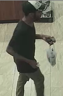 Side view of suspect wearing black and white TRUMP ball cap and a black shirt.